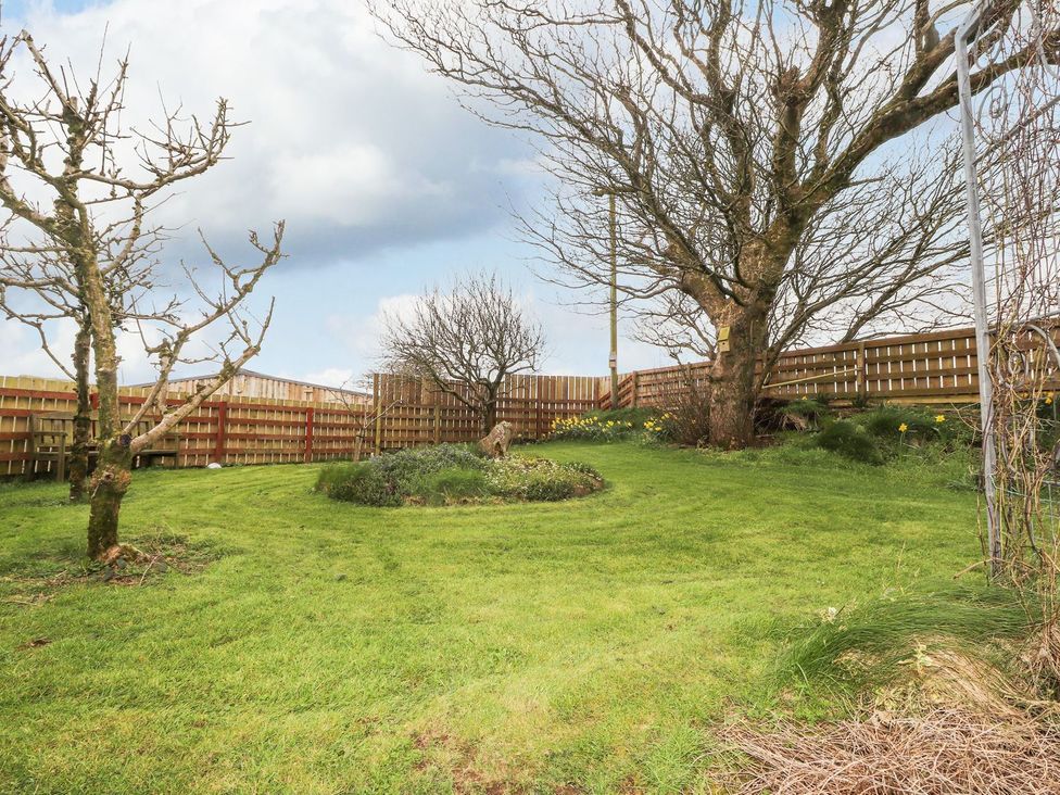 A garden with trees and a flower bed at Clawddcam in Mathry