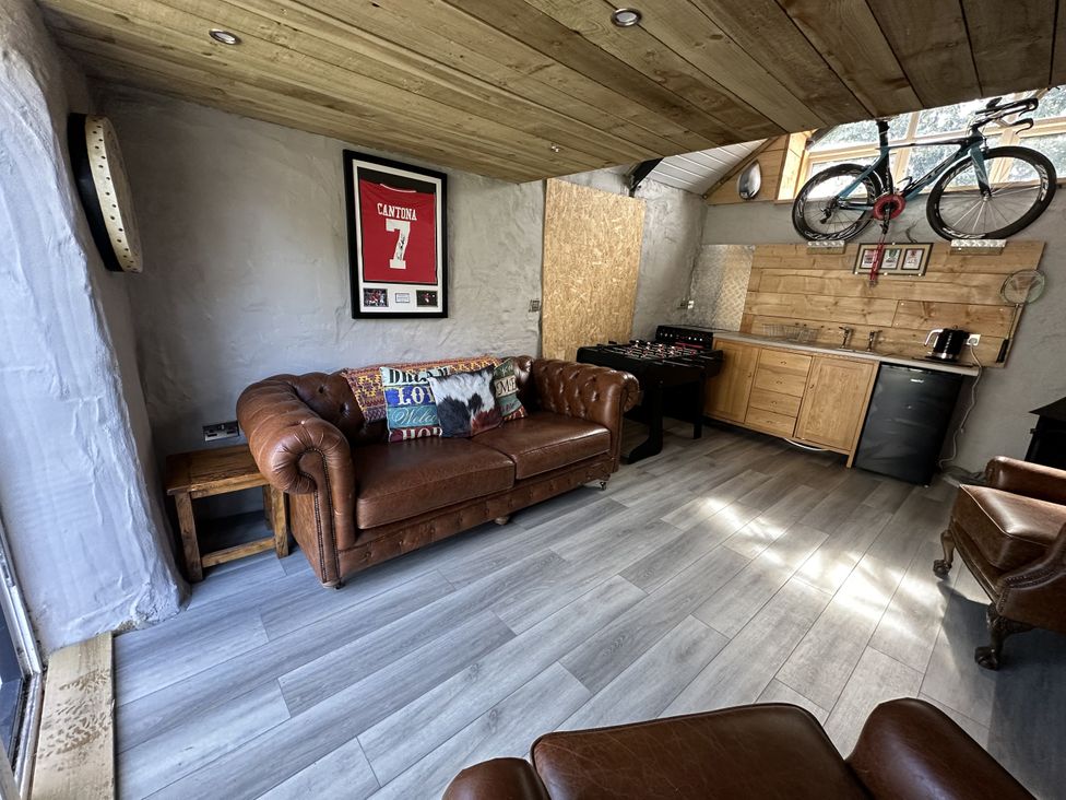 A snug with a leather sofa and kitchen area at Clawddcam in Mathry