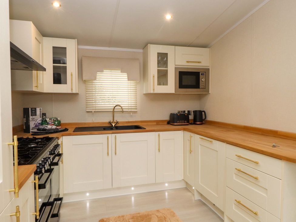 A kitchen with a sink and kitchen appliances at The Chalet at Tyn Lon in Chwilog