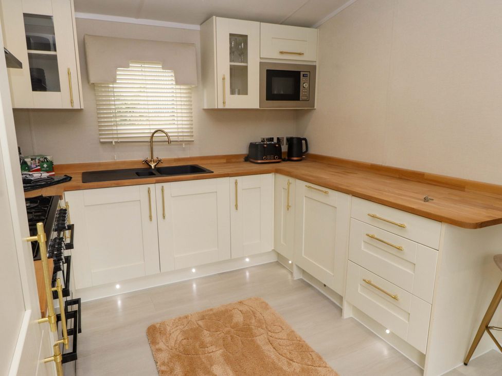 A kitchen with sink and microwave at The Chalet at Tyn Lon, Chwilog