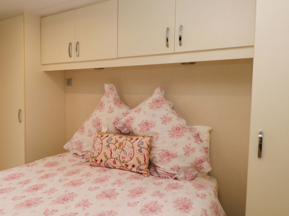 A bedroom with a bed and pillows at The Chalet at Tyn Lon Chwilog