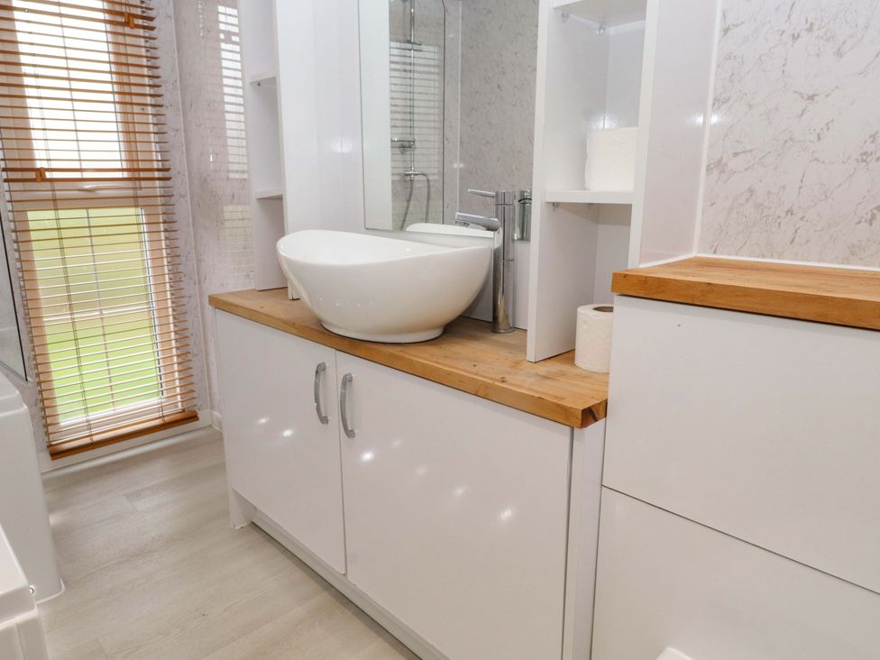 A bathroom with a sink and cabinet at The Chalet at Tyn Lon in Chwilog