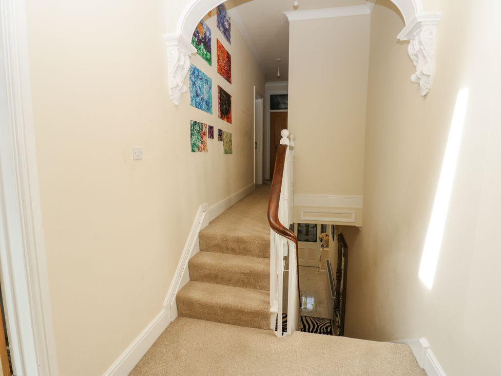 A hallway with stairs and wall art at St Ronans in Bishop Auckland