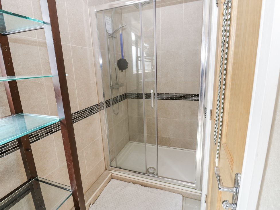 A bathroom with a glass shower enclosure and shelves at St Ronans Bishop Auckland