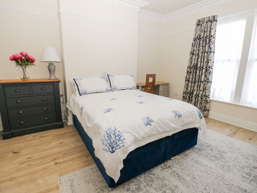 A bedroom with a bed, dresser, and vase of flowers at St Ronans in Bishop Auckland