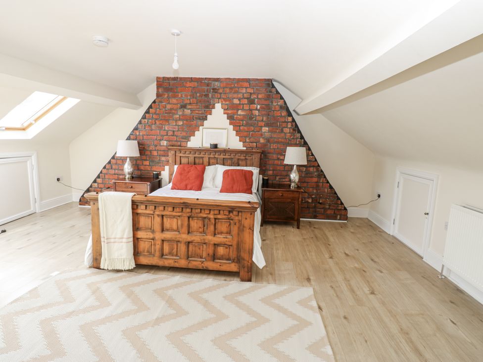 A bedroom with a wooden bed and red pillows at St Ronans in Bishop Auckland