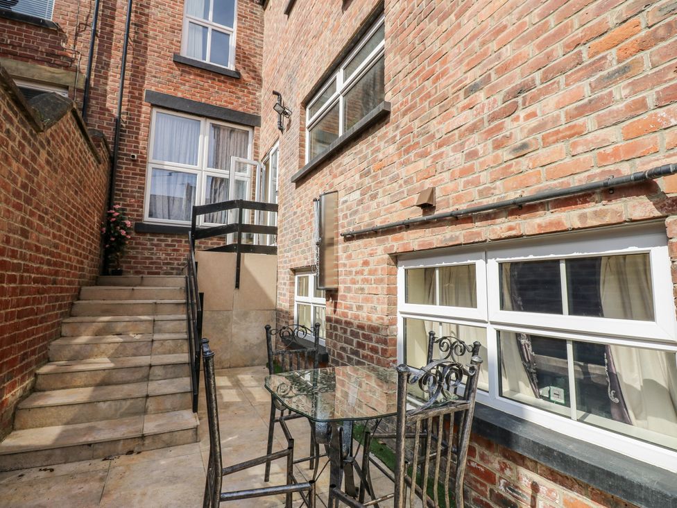 An outdoor area with a table and chairs near the brick wall at St Ronans in Bishop Auckland