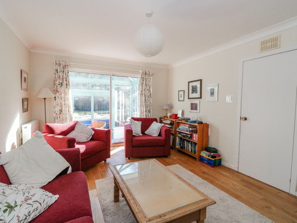 A living room with a red sofa and a bookshelf at Grianach in Balnaguard near Strathtay