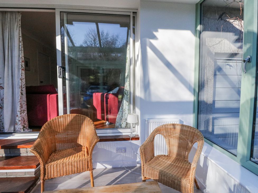 A conservatory with wicker chairs and a table at Grianach in Balnaguard near Strathtay