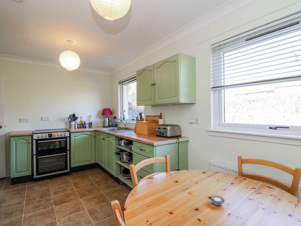 A kitchen with cabinets, oven, and a table at Grianach in Balnaguard near Strathtay