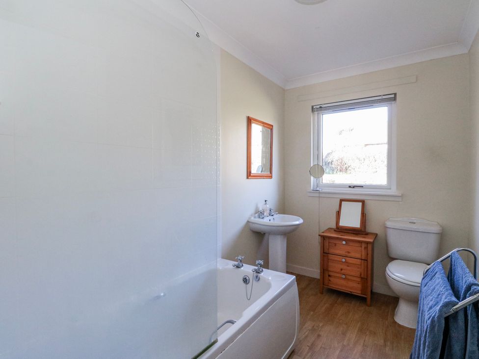 A bathroom with a bathtub, toilet, sink and wooden cabinet at Grianach in Balnaguard near Strathtay