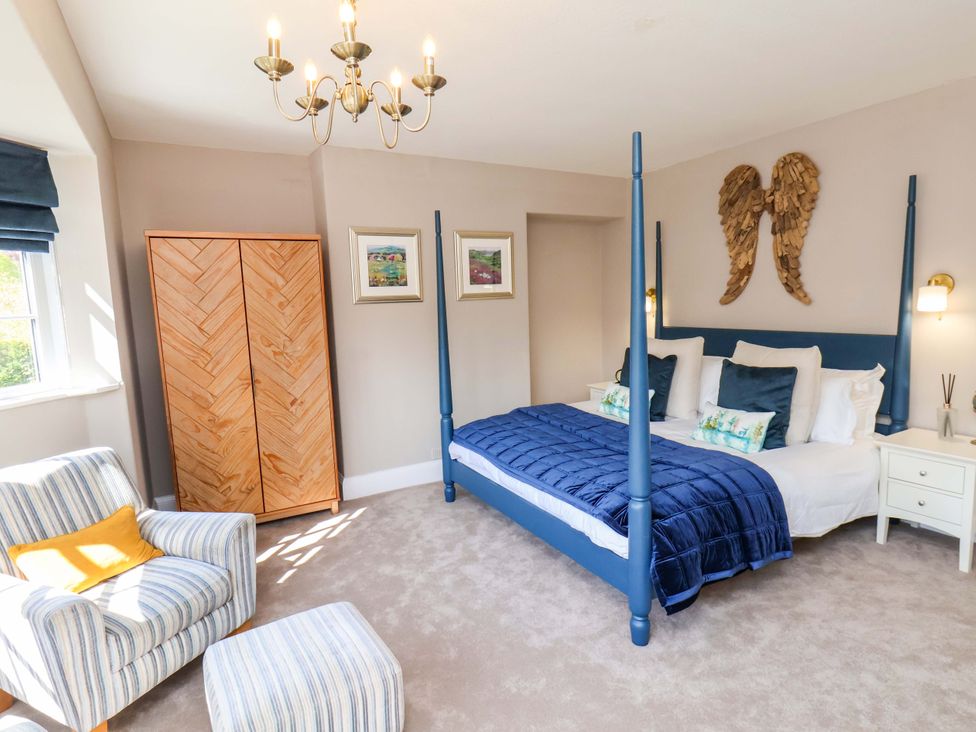 A bedroom with a four-poster bed and armchair at 16 High Street