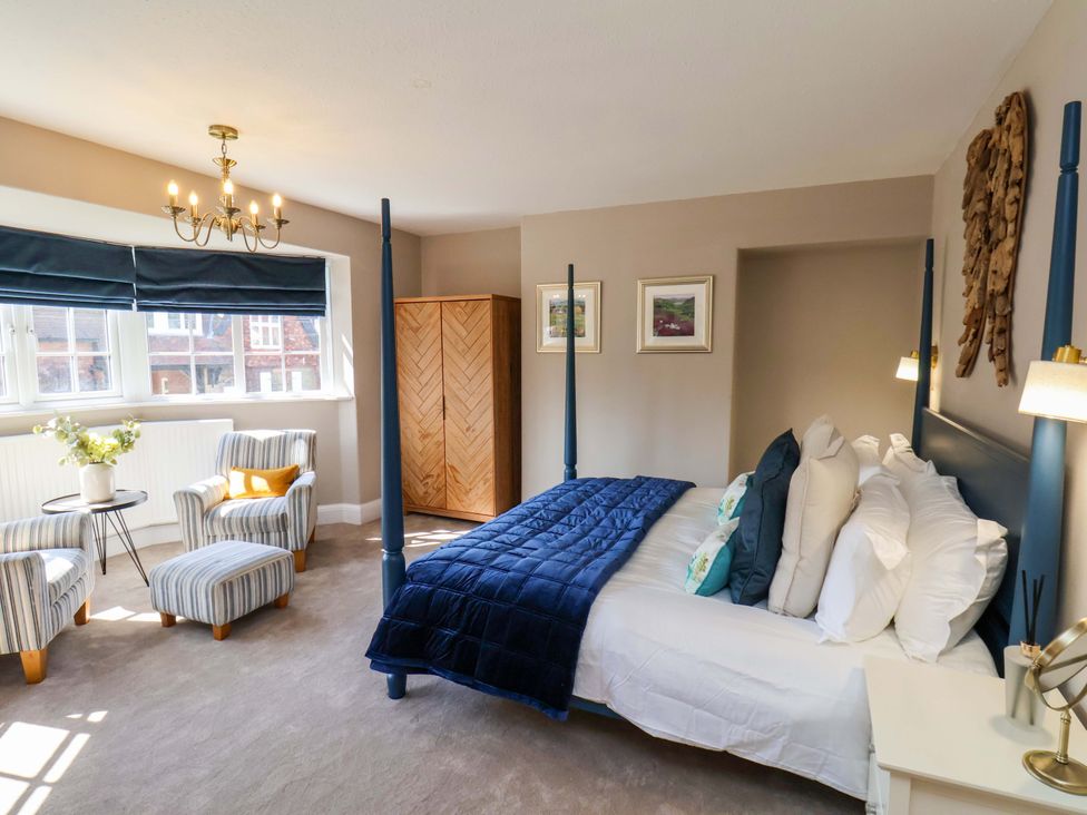 A bedroom with a bed and armchair at 16 High Street