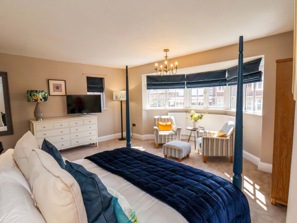 A bedroom with a bed, TV, and armchairs at 16 High Street