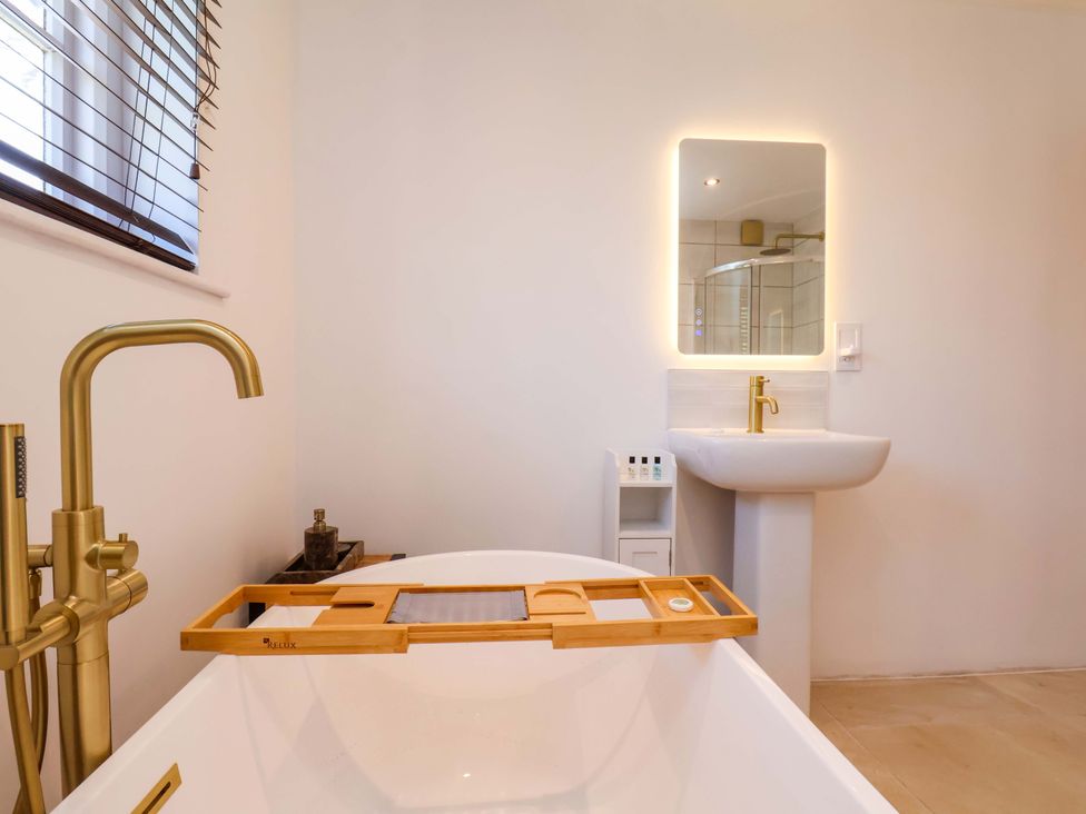 A bathroom with a bathtub, sink, and mirror at 16 High Street
