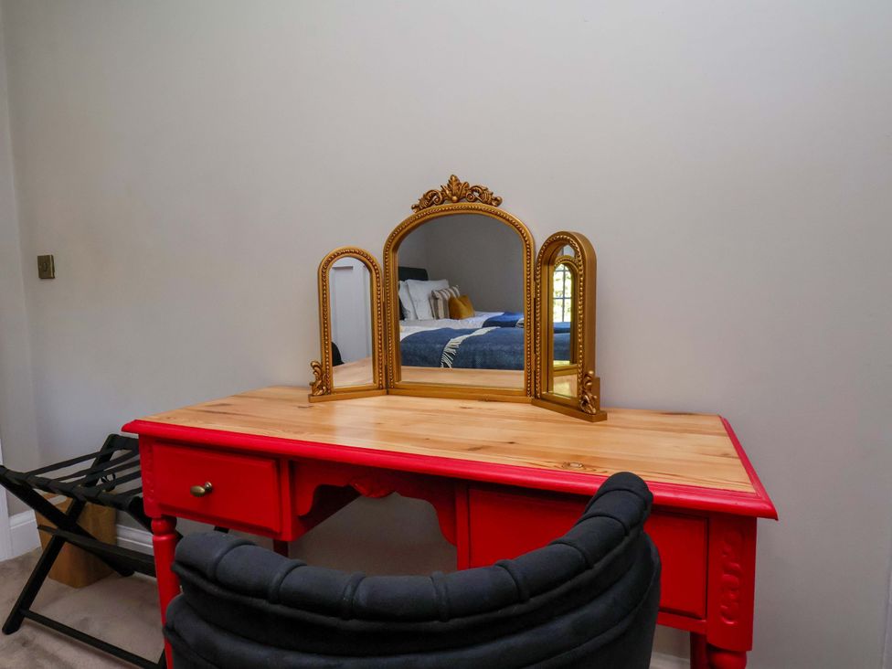 A vanity table with a mirror and chair in a bedroom at 16 High Street
