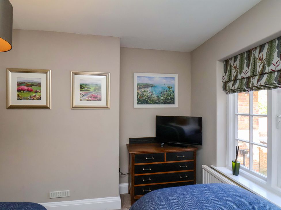 A bedroom with paintings on the wall and a television at 16 High Street