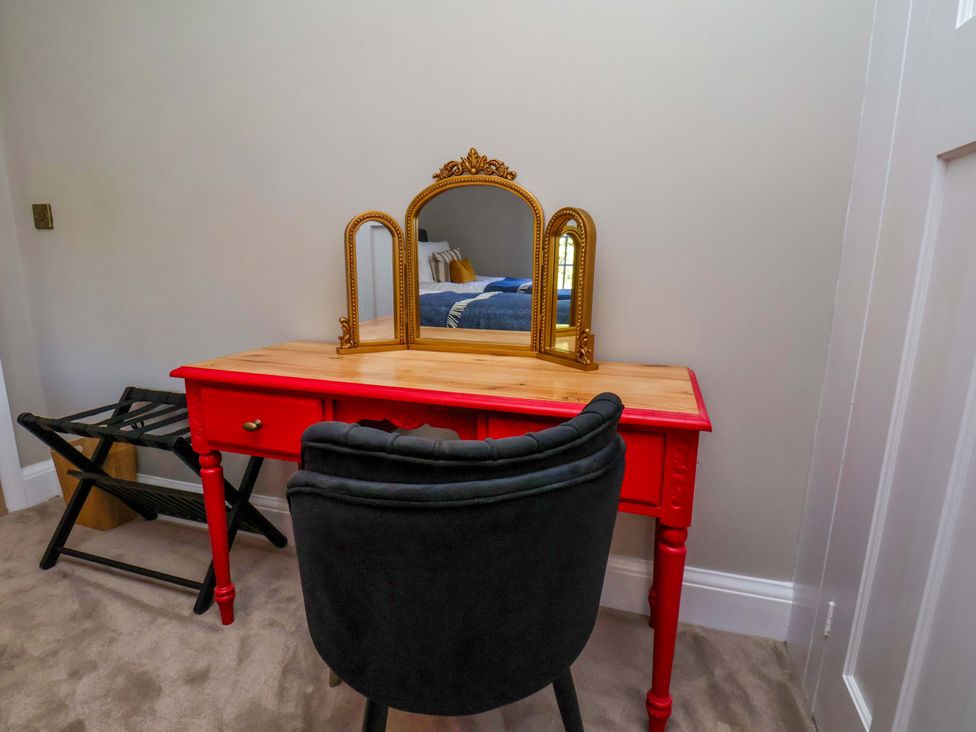 A vanity table with a mirror and chair in a bedroom at 16 High Street