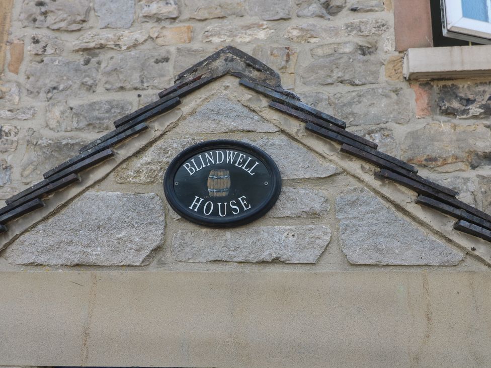 A sign for Blindwell House on a stone wall exterior