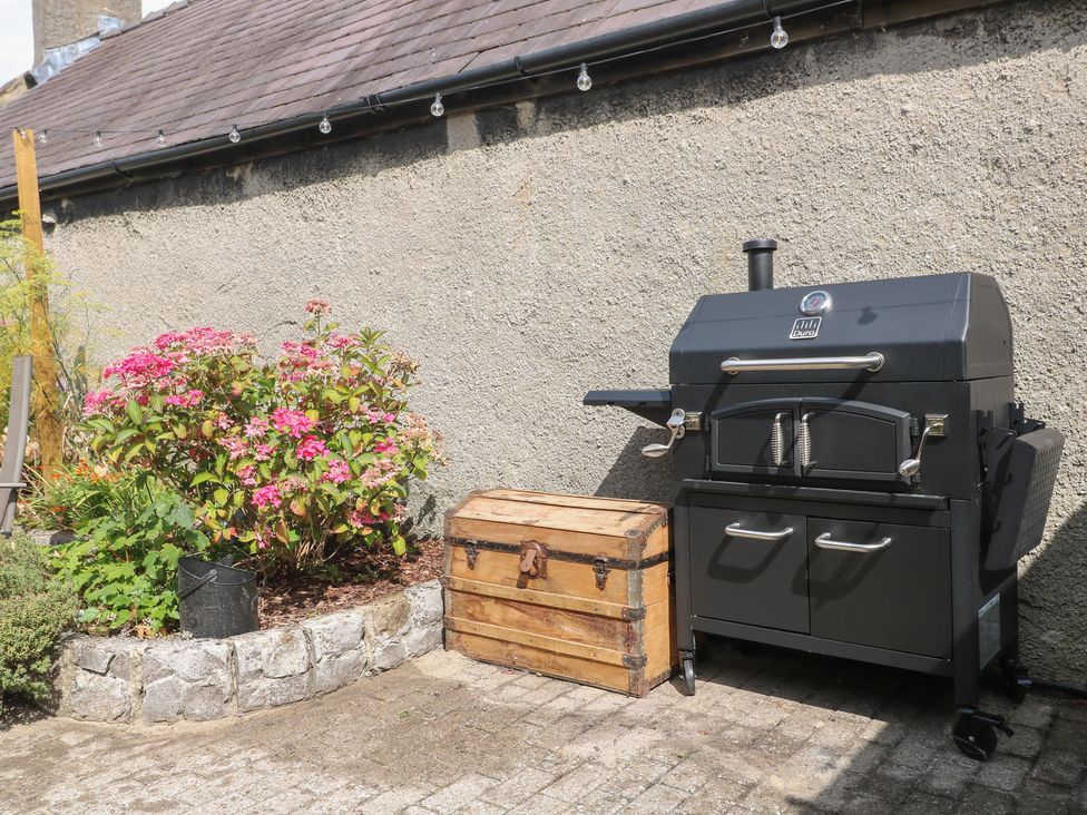 A barbecue grill and a wooden box near flowers on a patio at Blindwell House