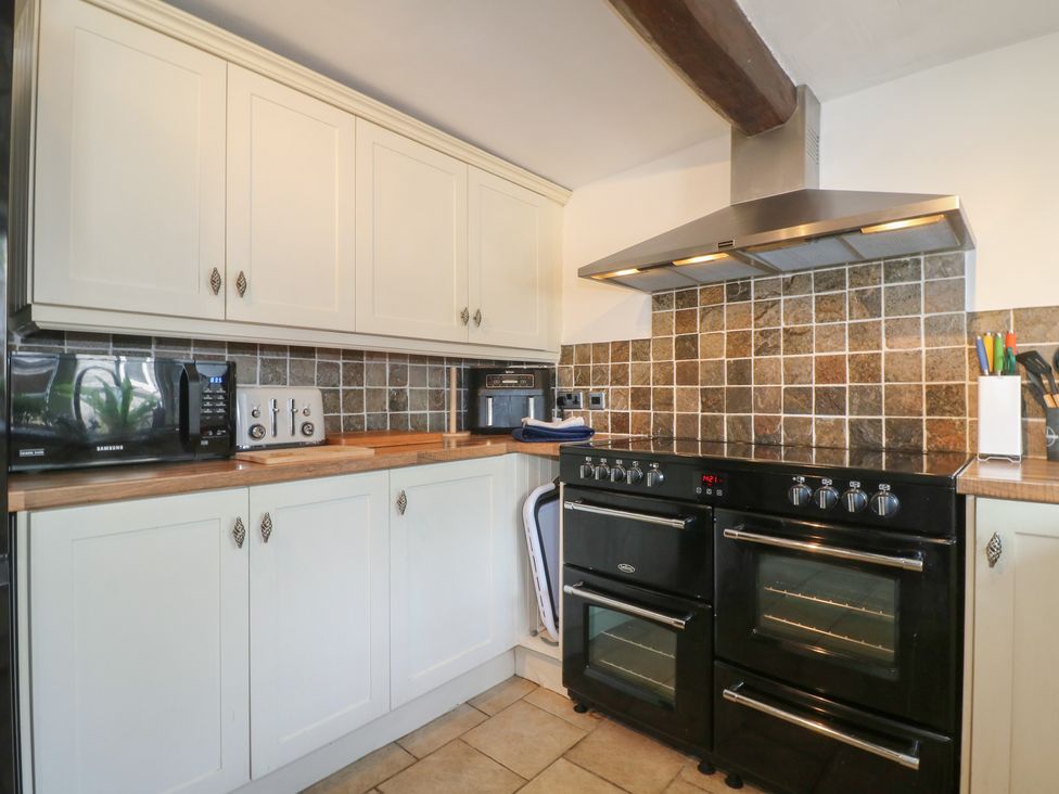 A kitchen with cabinets, countertop, microwave, cooker, and kitchen hood at Blindwell House