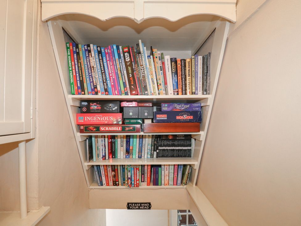 A shelf with books and board games at Blindwell House