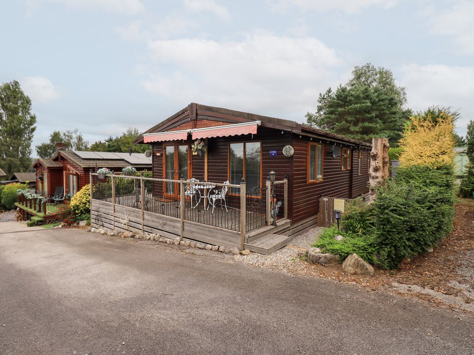 A wooden cabin with a deck and outdoor furniture at Charnwood
