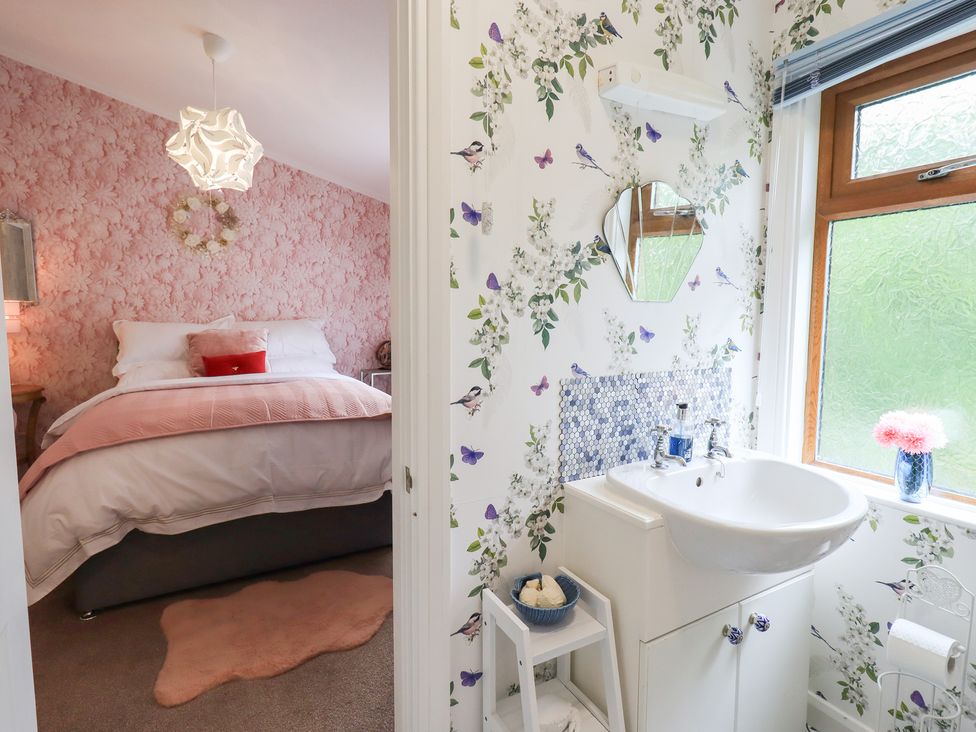 A bathroom with a sink and floral wallpaper at Charnwood in 