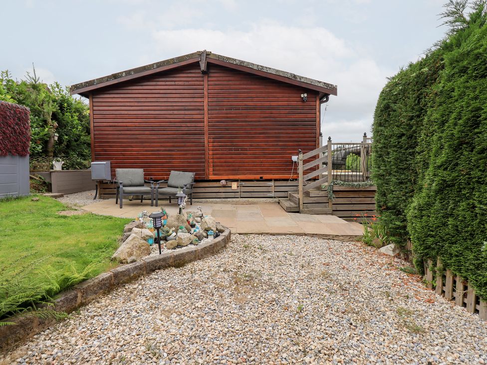 A garden with a wooden cabin and seating area at Charnwood