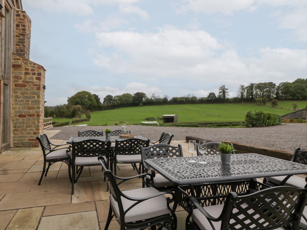 An outdoor seating area with a table and chairs at Two Parks Barn in Upton Bishop near Ross-On-Wye