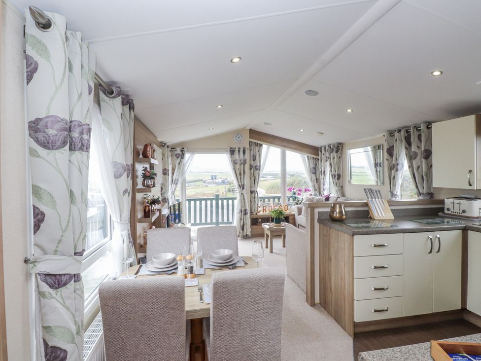 A living room with view windows and kitchen features at Bryncrin Edern