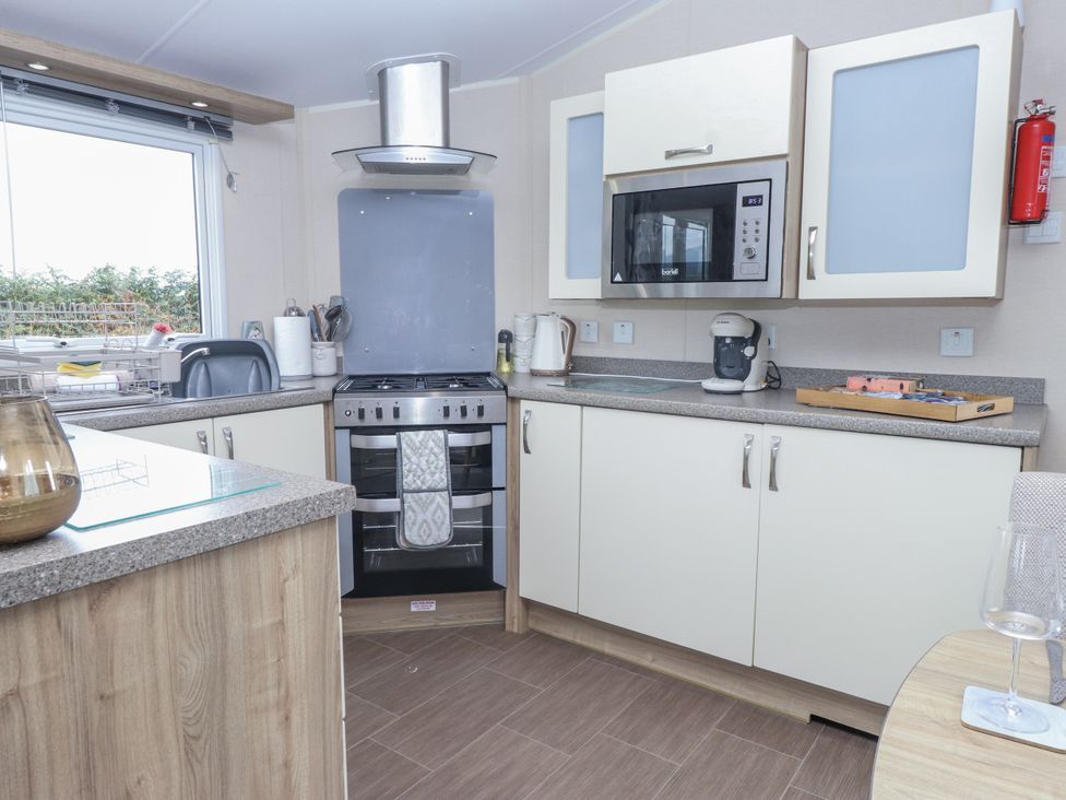 A kitchen with a stove, microwave, sink and cabinets at Bryncrin in Edern