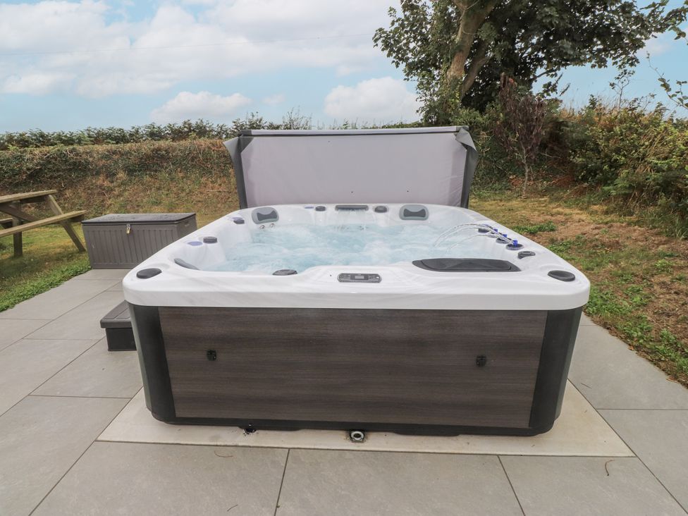 A hot tub in a garden with a storage unit at Bryncrin Edern