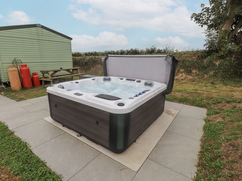 A hot tub with a bench and gas cylinders at Bryncrin in Edern