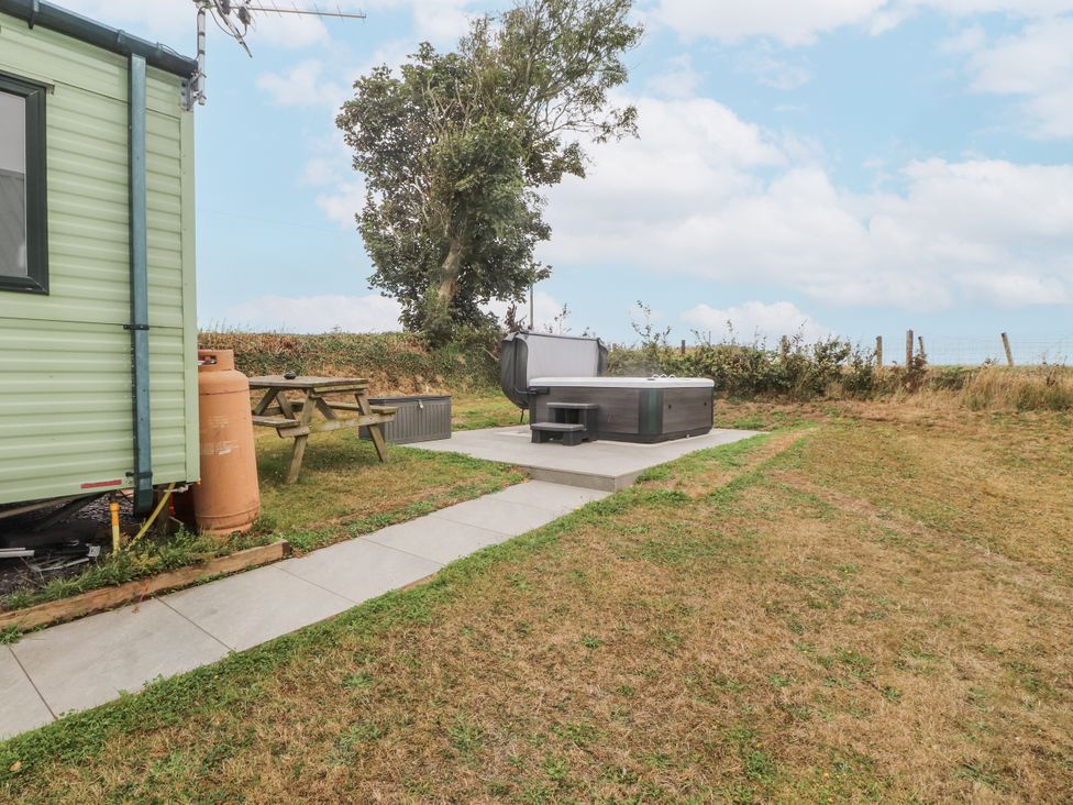 A hot tub and picnic table in a garden at Bryncrin Edern