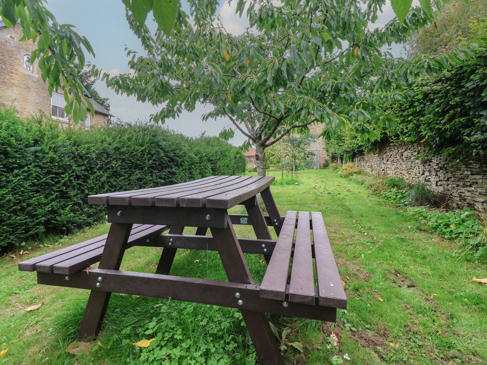 A picnic table in a garden with grass and a tree at The Annex at Manor Farm