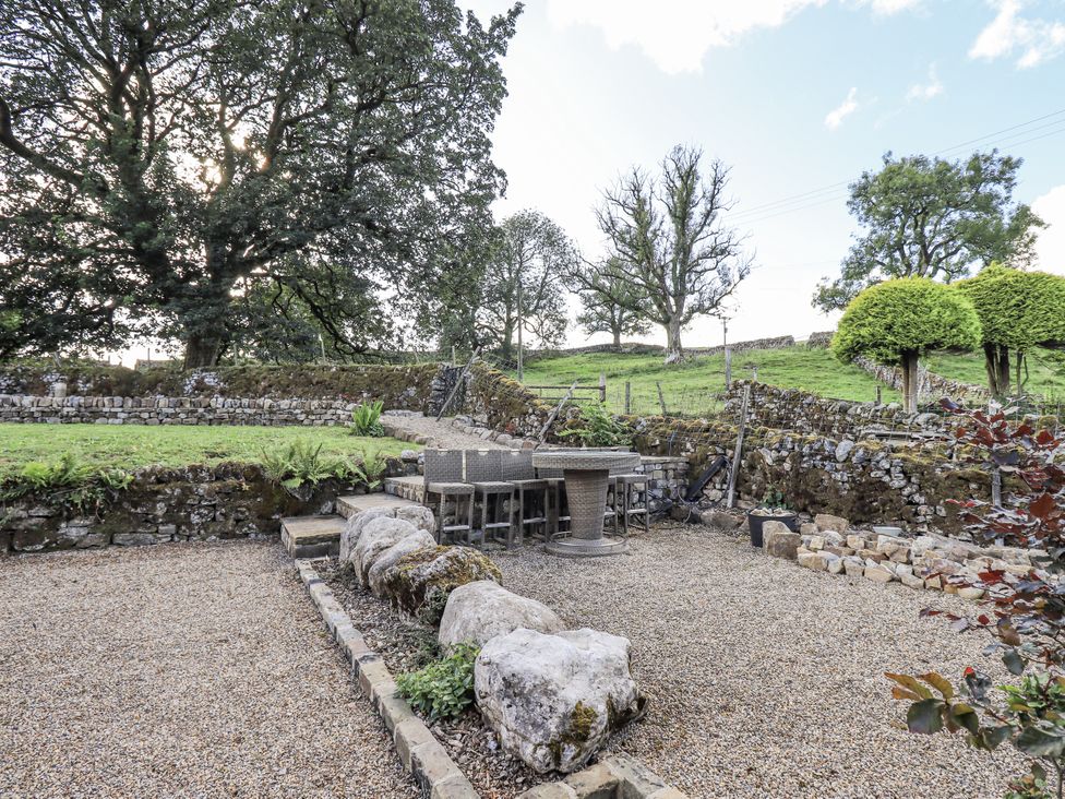 A garden with a table and chairs surrounded by stones at Hallbeck near Kettlewell
