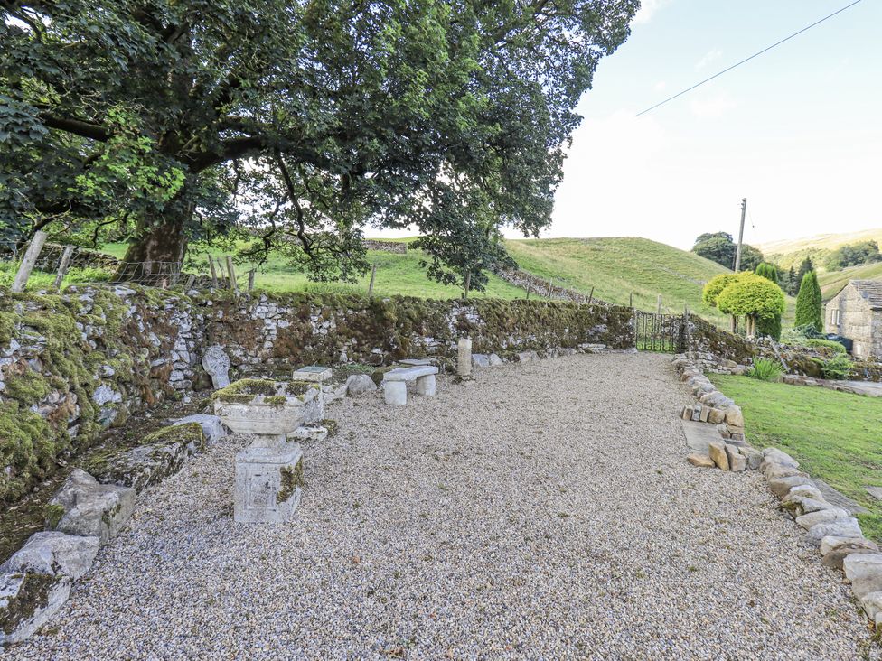 A garden area with gravel, stone walls, and seating at Hallbeck near Kettlewell
