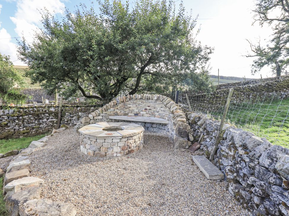 An outdoor area with a stone bench and round table at Hallbeck near Kettlewell