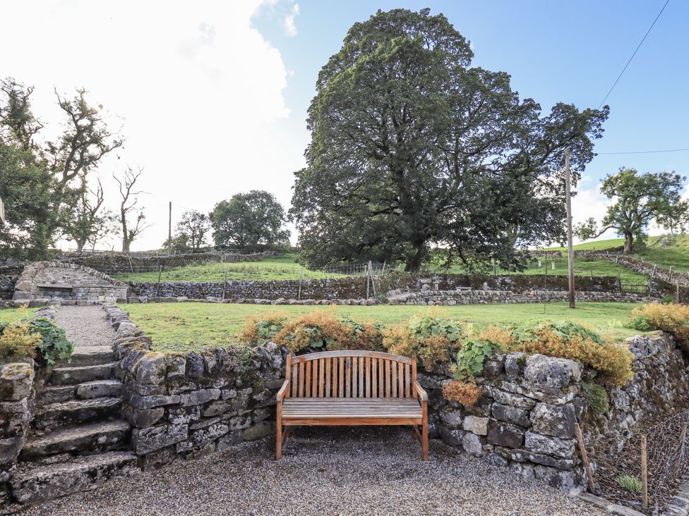 An outdoor area with a bench and stone wall at Hallbeck near Kettlewell