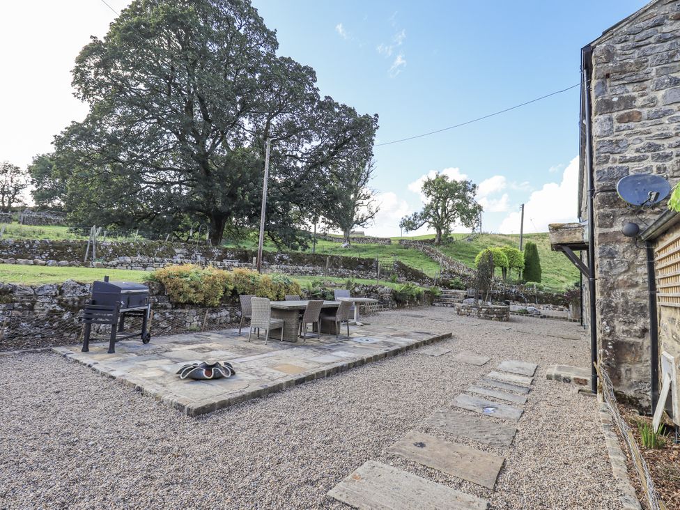 An outdoor patio area with a grill and dining table at Hallbeck near Kettlewell