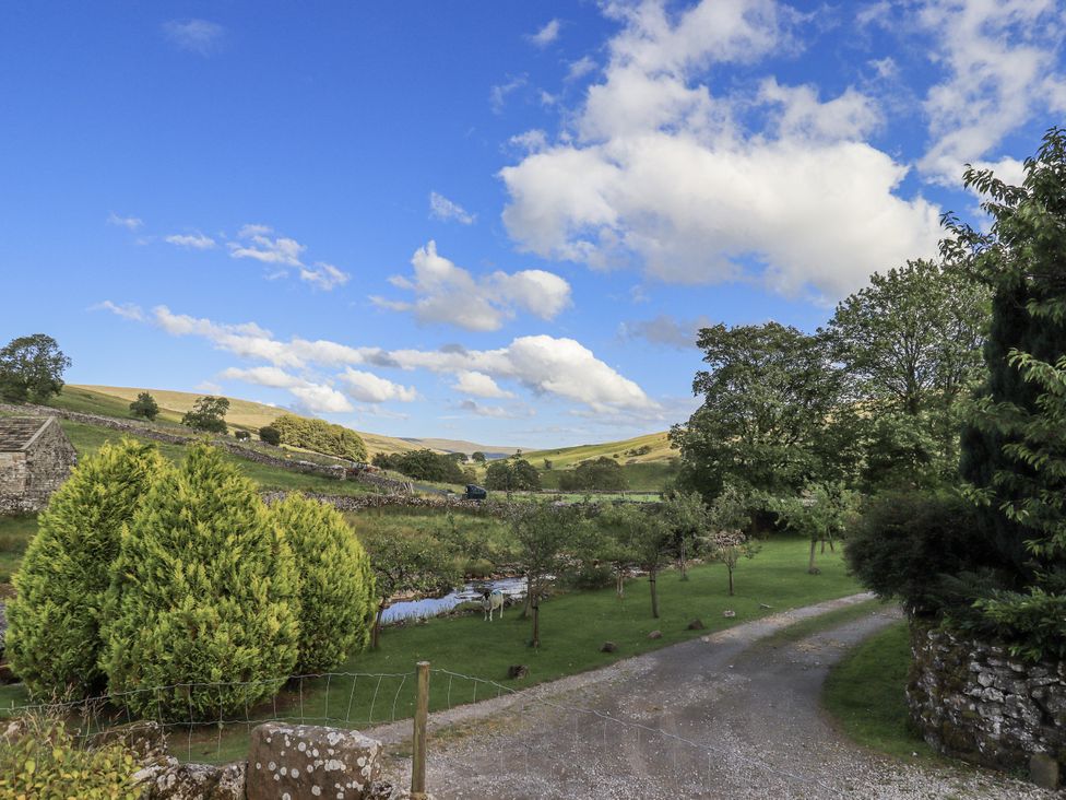 A garden with trees and a road at Hallbeck near Kettlewell