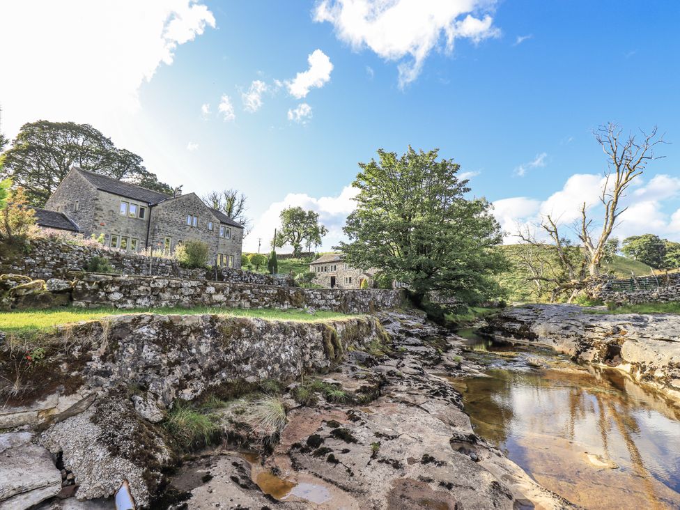 A view of a stone house and water source at Hallbeck near Kettlewell