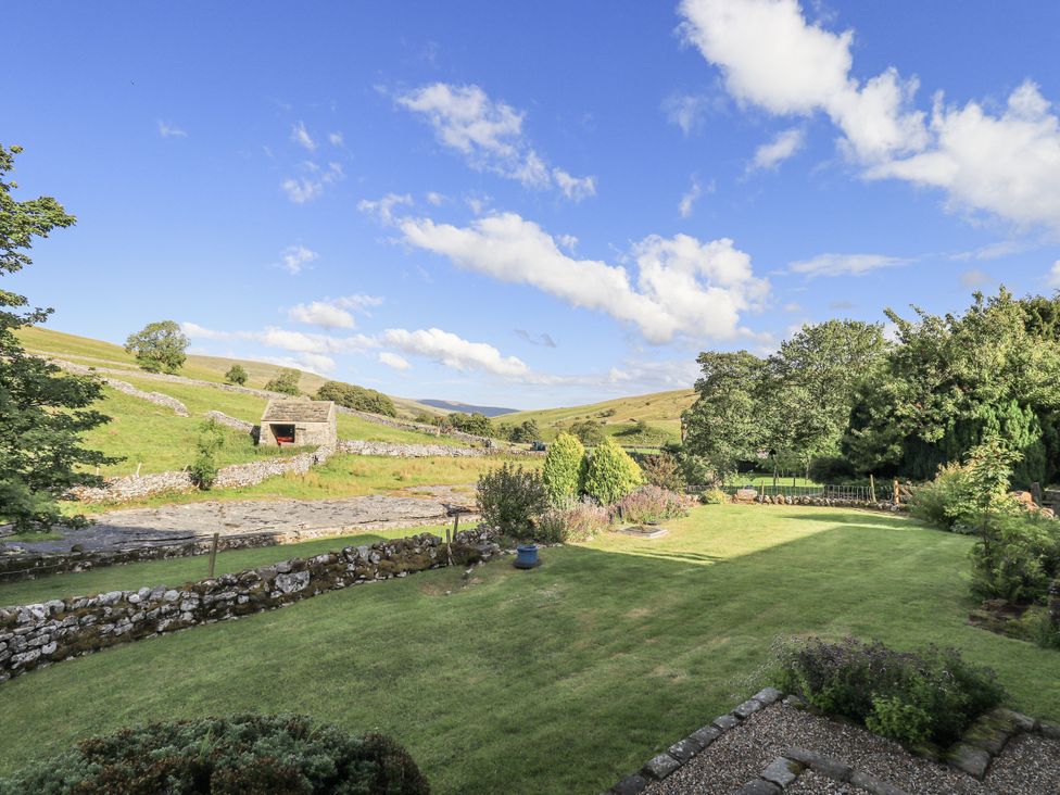 A garden with grass, trees and a stone wall at Hallbeck near Kettlewell