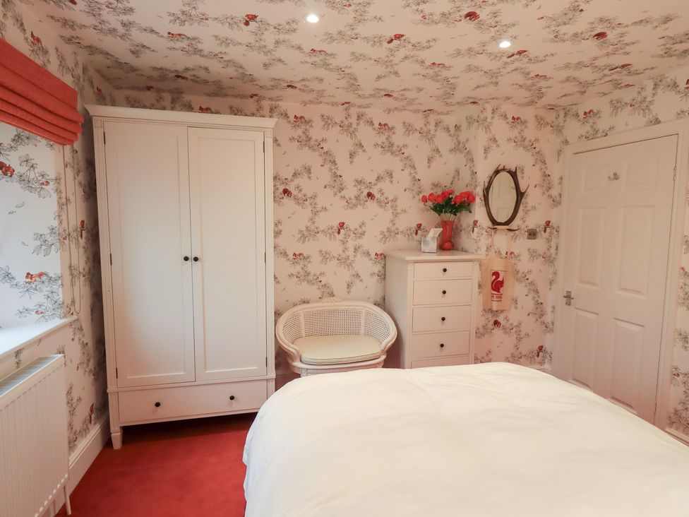 A bedroom with a wardrobe, chair, and drawers at Hallbeck in Buckden