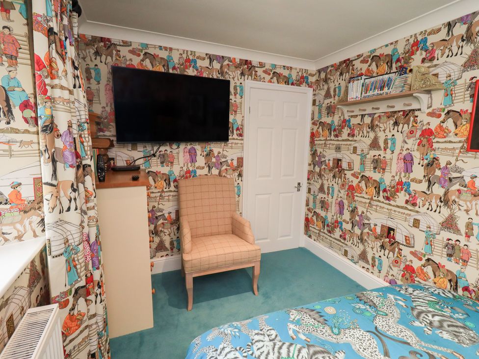 A bedroom with a television and chair at Hallbeck in Buckden