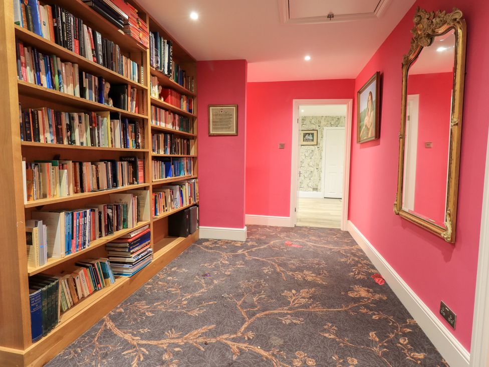 A hallway with a bookshelf and mirror at Hallbeck in Buckden
