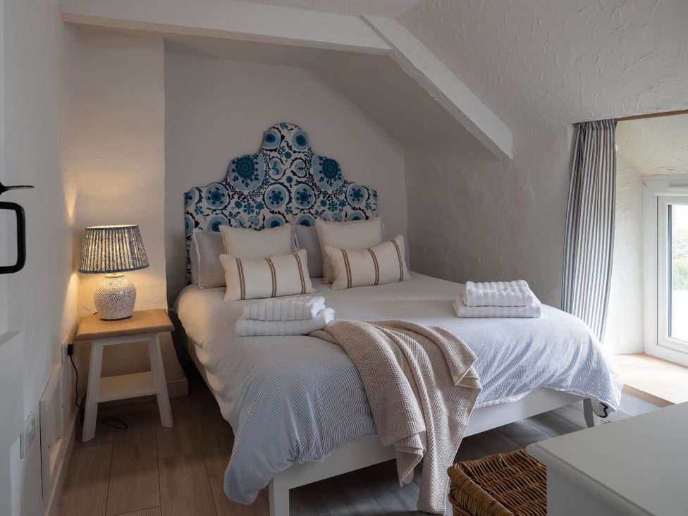 A bedroom with a bed and a lamp at Rose Cottage in Wadebridge