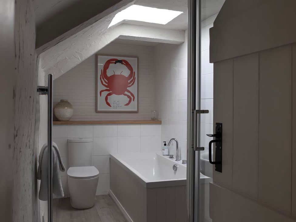 A bathroom with a bathtub and toilet at Rose Cottage in Wadebridge