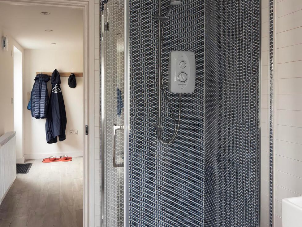 A bathroom with a shower and coat hooks at Rose Cottage in Wadebridge